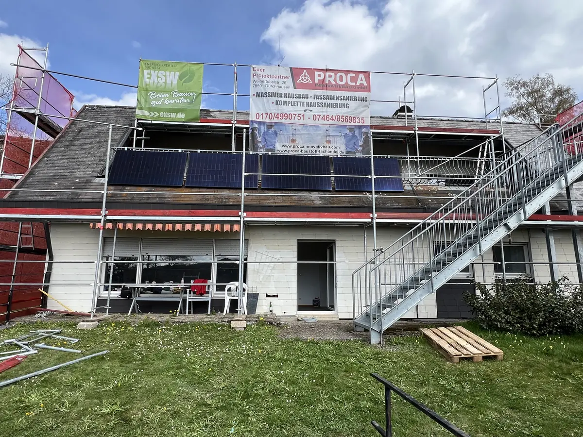 Das Einfamilienhaus vor der Sanierung, eingerüstet mit Proca-Bautafel