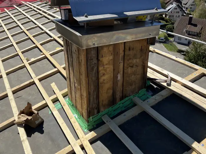 Kaminkopf mit Holzverkleidung, umgeben von der neuen Lattung