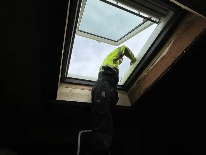 Handwerker setzt von innen ein Dachfenster ein