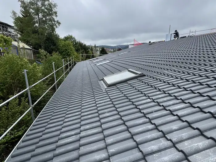 Fertiges Dach mit grauen Dachsteinen und Dachfenster