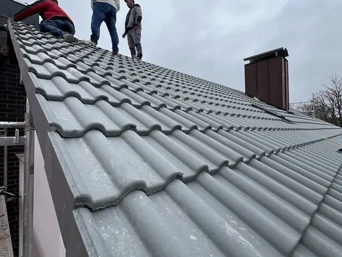 Zwei Dachdecker auf dem First des fertig eingedeckten Daches