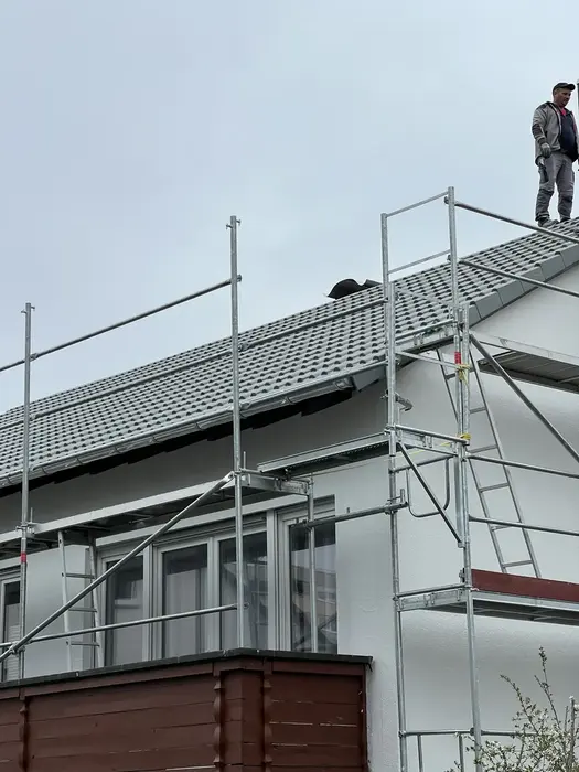 Saniertes Gebäude mit neuem Dach und heller Fassade, Gerüst steht noch