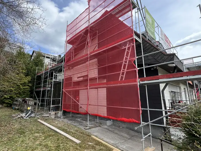 Gerüst mit rotem Schutznetz an der Giebelseite des Wohnhauses