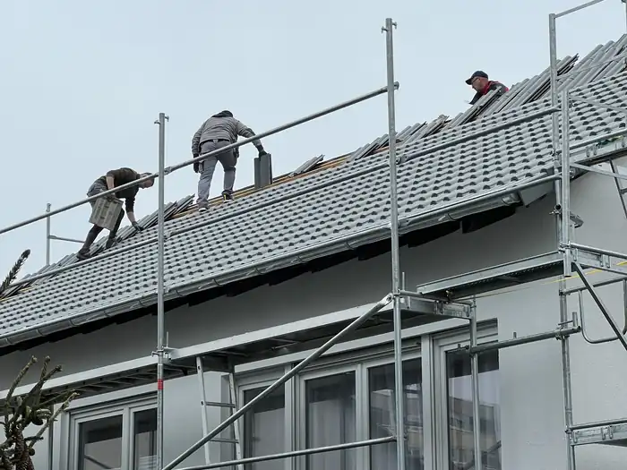 Dachdecker auf dem grauen Dach eines langen Wohngebäudes