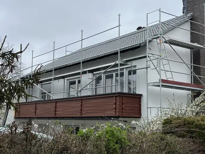 Langes Wohngebäude mit Balkon, neuem Dach und Gerüst