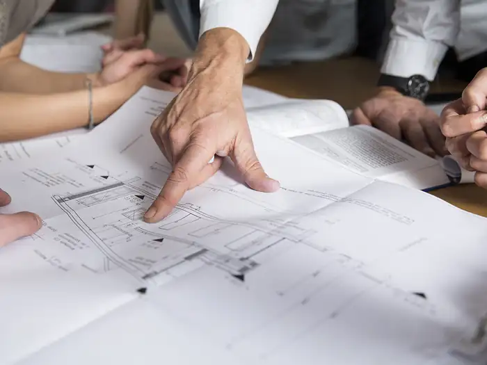 Hände über einem Bauplan während der Planungsbesprechung