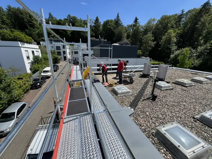 Arbeiten auf dem Flachdach mit Absturzsicherung und Materialtransport